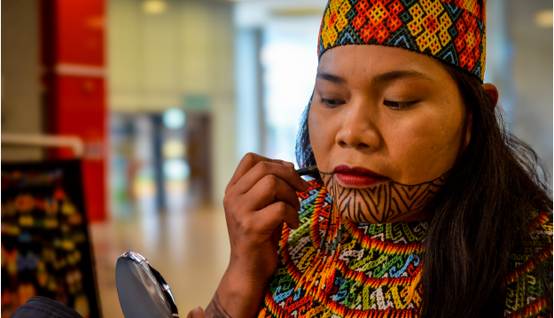 Mujer indígena realiza su maquillaje tradicional para presentaicón musical